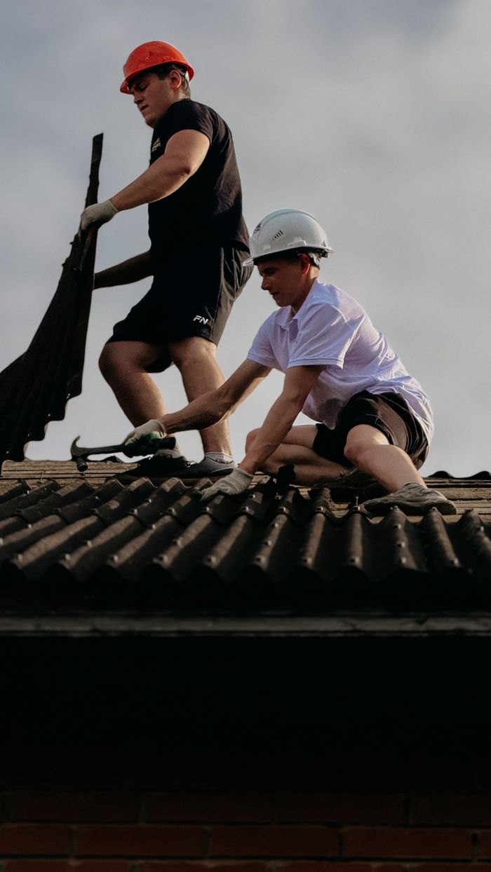 Mastering the First Impression: Your intriguing post title goes here Two construction workers fixing roof tiles, emphasizing teamwork and safety with helmets.