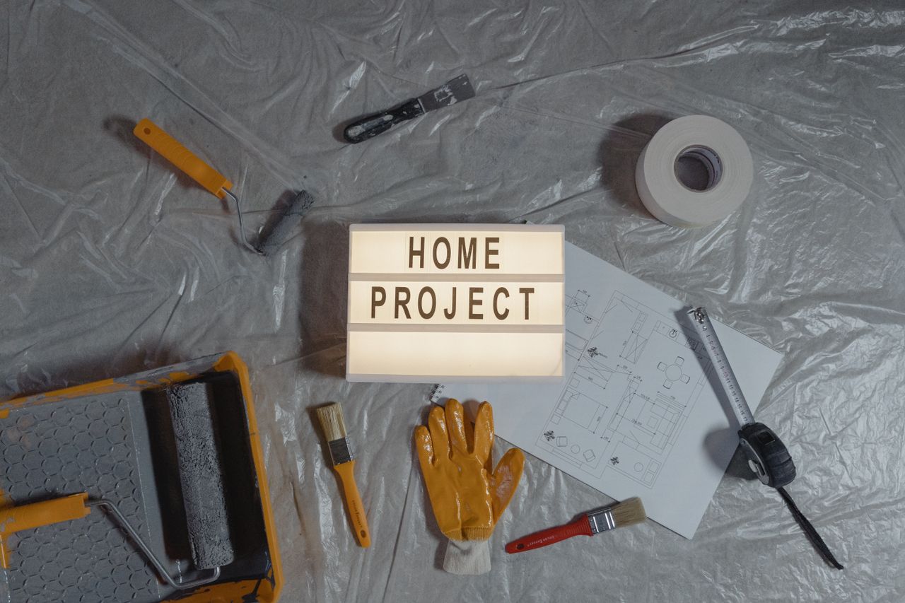 The Art of Drawing Readers In: Your attractive post title goes here Flat lay of home improvement setup with tools, gloves, and floor plan for DIY projects.
