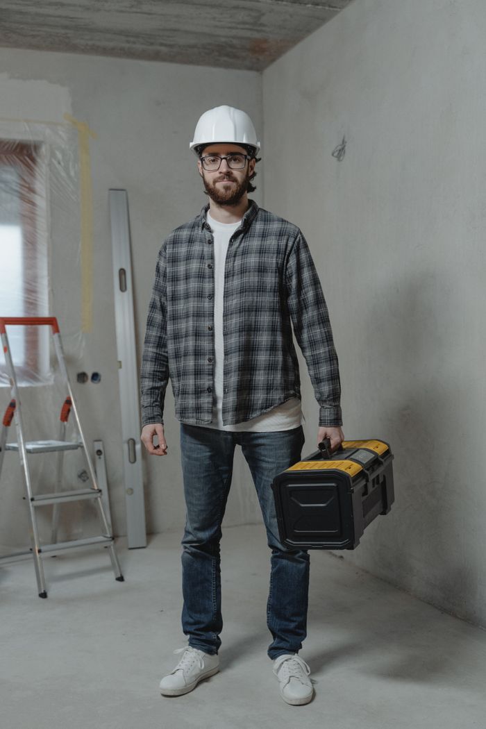 Crafting Captivating Headlines: Your awesome post title goes here Construction worker in plaid shirt with toolbox indoors, showcasing renovation setting.